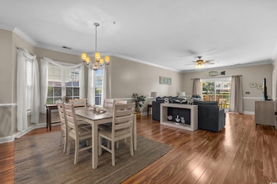 Dining area with ornamental molding, dark wood-style flooring, a chandelier, and ceiling fan