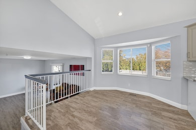 Empty room featuring light wood finished floors, high vaulted ceiling, and recessed lighting