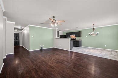 Unfurnished living room featuring hardwood / wood-style floors, ceiling fan with notable chandelier, and ornamental molding