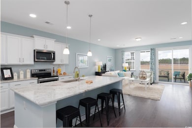 Kitchen with appliances with stainless steel finishes, a sink, white cabinets, a breakfast bar area, and dark wood-style floors