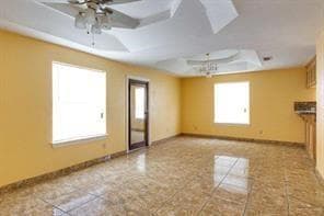 Unfurnished room with tile patterned floors, baseboards, a raised ceiling, and ceiling fan