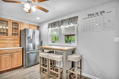 Kitchen with light hardwood / wood-style flooring, ceiling fan, stainless steel fridge, and a kitchen bar