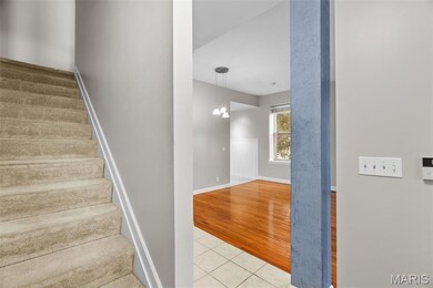 Stairs with tile patterned flooring and a chandelier