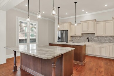 Kitchen featuring a kitchen island, stainless steel fridge, a sink, cream cabinetry, and decorative backsplash