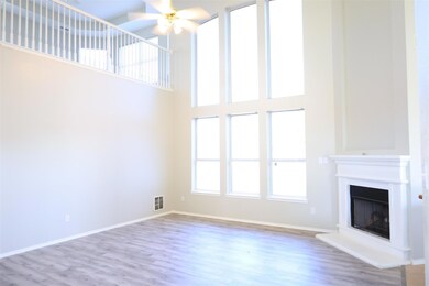 Unfurnished living room with ceiling fan, a towering ceiling, and light wood-type flooring