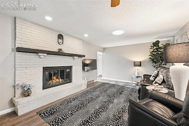 Living area with a textured ceiling, luxury vinyl floors, a brick gas fireplace, and recessed lighting