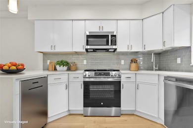 Kitchen with stainless steel appliances, a sink, light countertops, white cabinetry, and tasteful backsplash