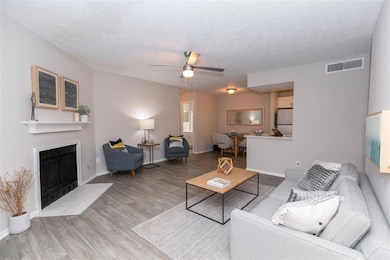 Living room featuring a textured ceiling, ceiling fan, and light wood-type flooring