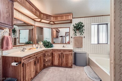 Bathroom featuring a sink, a garden tub, wallpaper