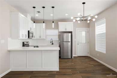 Kitchen featuring stainless steel appliances, white cabinetry, a peninsula, wood finish floors, and recessed lighting