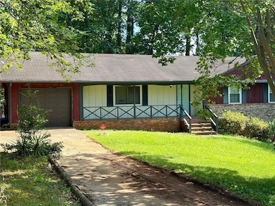 View of front of property featuring a porch, concrete driveway, an attached garage, a front yard, and brick siding