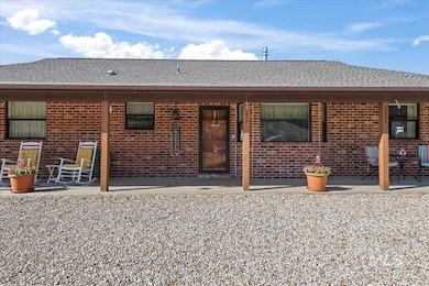 Rear view of house with roof with shingles, brick siding, and a patio area