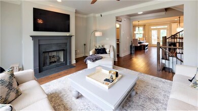 Living area with wood finished floors, crown molding, ceiling fan, a fireplace, and stairs