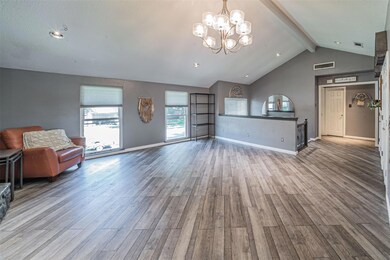 Unfurnished living room featuring a notable chandelier, lofted ceiling with beams, and wood-type flooring