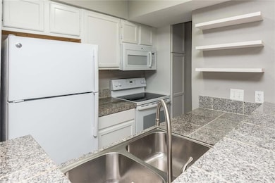 Kitchen with tile counters, white appliances, whi
