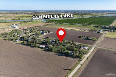 Aerial view of property and surrounding area featuring rows of crops, rural landscape, and a large body of water