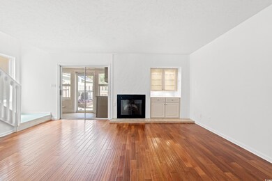 Unfurnished living room featuring hardwood / wood-style floors, a glass covered fireplace, and a textured ceiling