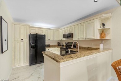 Kitchen featuring light stone counters, cream cabi