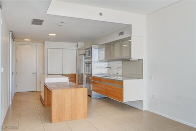 Kitchen featuring light tile patterned floors, modern cabinets, glass insert cabinets, and a kitchen island