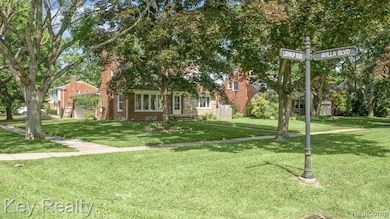 Sun-drenched corner view with mature trees, manicured lawn, and stylish signpost