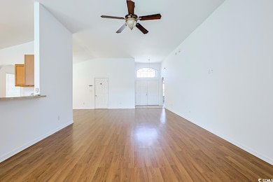 Unfurnished living room featuring dark wood-style flooring, vaulted ceiling, and ceiling fan