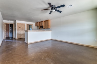 Unfurnished living room featuring finished concrete floors, ceiling fan, and a textured ceiling