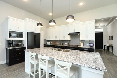 Enter the heart of your home, where a designer 16 x 11 Chef's kitchen awaits. Adorned with luxurious Bianco Primata granite countertops, a subway backsplash, pendant lighting, black S/S appliances, a generously sized island featuring a convenient breakfast bar, and upgraded soft-close Shaker cabinets, this culinary space is as functional as it is stylish.