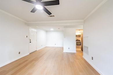 Spare room featuring light wood-style flooring, ornamental molding, and a ceiling fan