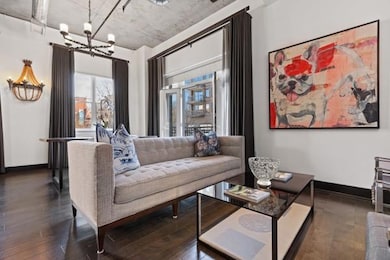 Living area with baseboards, wood finished floors, and an inviting chandelier