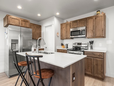Kitchen with light wood-style flooring, stainless steel appliances, a kitchen breakfast bar, recessed lighting, and an island with sink