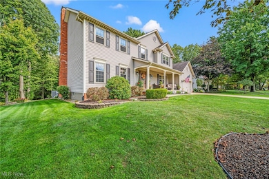 View of front of home with covered porch, a front yard, a chimney, and a garage