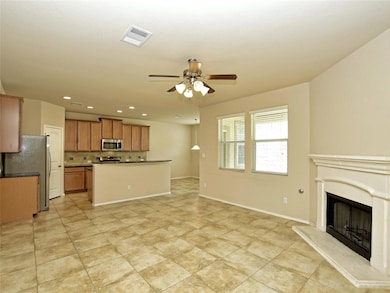 Kitchen featuring dark countertops, decorative backsplash, open floor plan, a fireplace with raised hearth, and recessed lighting