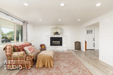 Living room with recessed lighting, wood finished floors, a stone fireplace, and a textured ceiling