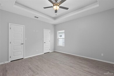 Spare room featuring a tray ceiling, wood finished floors, and a ceiling fan