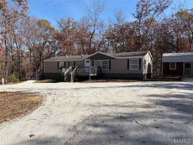 Manufactured / mobile home featuring a deck, gravel driveway, and an outdoor structure