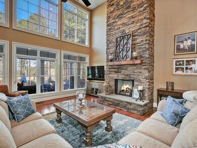 Inviting two story family room with wall of windows overlooking the pool and golf course