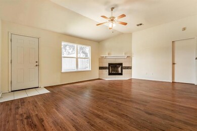 Unfurnished living room featuring wood finished floors, ceiling fan, vaulted ceiling, and a tile fireplace