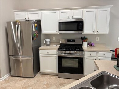 Kitchen featuring stainless steel appliances, light countertops, and white cabinets