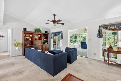 Living area with ornamental molding, carpet flooring, ceiling fan, and lofted ceiling