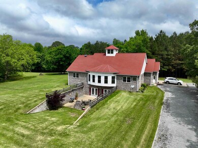 Back of house featuring a lawn, a view of trees, driveway, and brick siding