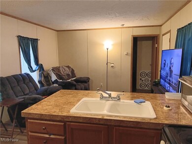 Kitchen featuring a decorative wall, ornamental molding, open floor plan, a textured ceiling, and electric stove