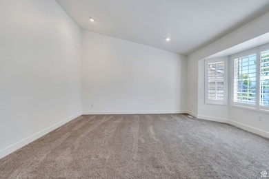 Empty room with light carpet, vaulted ceiling, and recessed lighting