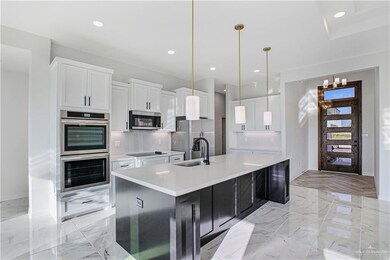 Kitchen with stainless steel appliances, a sink, a large island, white cabinetry, and decorative backsplash