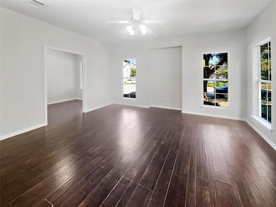 Unfurnished room featuring dark wood-type flooring and ceiling fan
