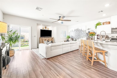 Living room with light wood finished floors, a ceiling fan, plenty of natural light, and recessed lighting
