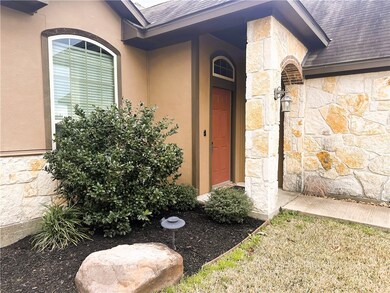 View of exterior entry with a shingled roof, stone