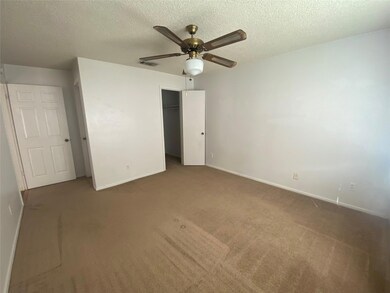 Unfurnished bedroom with a textured ceiling, carpet flooring, a closet, and a ceiling fan