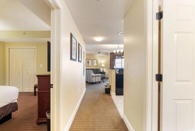 Hallway with an inviting chandelier, light carpet,