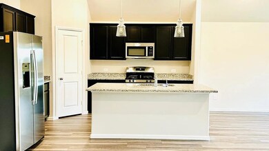Kitchen with light stone counters, a kitchen islan