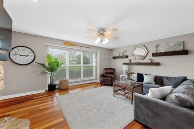 Living room has hardwood flooring, ceiling fan with light & opens to kitchen/breakfast room.
